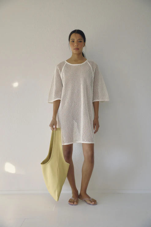 Bohème Goods Fisherman Tee in cream open net cotton worn as a beach coverup with jelly sandals and a lime green tote bag against a white studio background