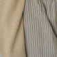 Close-up of Bohème Goods Stripe Barrel Pant showing multicolour cotton stripe fabric texture, elasticated waistband and front pocket detail alongside a camel knit sleeve