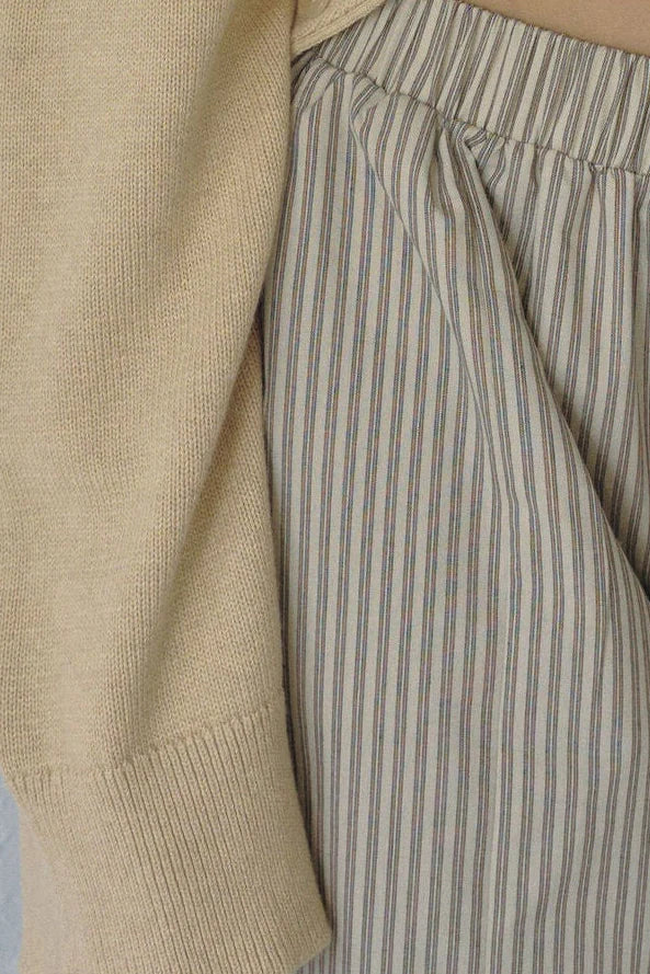 Close-up of Bohème Goods Stripe Barrel Pant showing multicolour cotton stripe fabric texture, elasticated waistband and front pocket detail alongside a camel knit sleeve