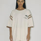 Bohème Goods Tourist Tee in cream full length front view showing oversized cotton silhouette, Club Bohème palm tree chest graphic and brown stripe sleeve detail, styled with matching Track Short