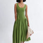 Woman wearing a meadow green linen midi dress with scoop neckline and voluminous panier skirt, holding pink peonies — Vivienne Dress by Eliza Faulkner at Ånde