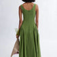 Woman wearing a meadow green linen midi dress with scoop neckline and voluminous panier skirt, holding pink peonies — Vivienne Dress by Eliza Faulkner at Ånde