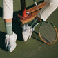Le Bon Shoppe Boyfriend Socks in meadow worn on a tennis court with white sneakers and cream trousers, styled with a vintage wooden tennis racquet showing sporty vintage double stripe detail
