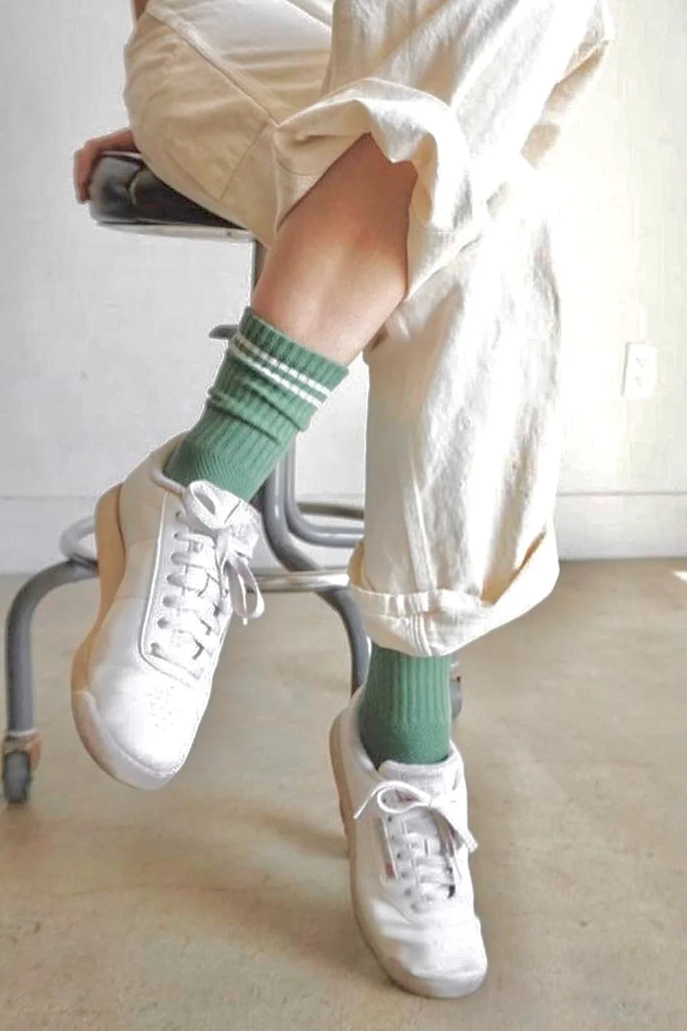 Le Bon Shoppe Boyfriend Socks in meadow worn with white sneakers and cream wide leg trousers, showing green ribbed cotton sock with white double stripe and longer-than-crew length