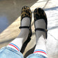 Le Bon Shoppe Boyfriend Socks in milk worn with leopard print Mary Jane flats and light wash jeans, showing white ribbed cotton sock with red and blue double stripe in natural sunlight