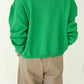 Back view of Le Bon Shoppe Cotton Leila Cardigan in spring green showing relaxed oversized silhouette, ribbed hem and cuffs, styled with cream trousers