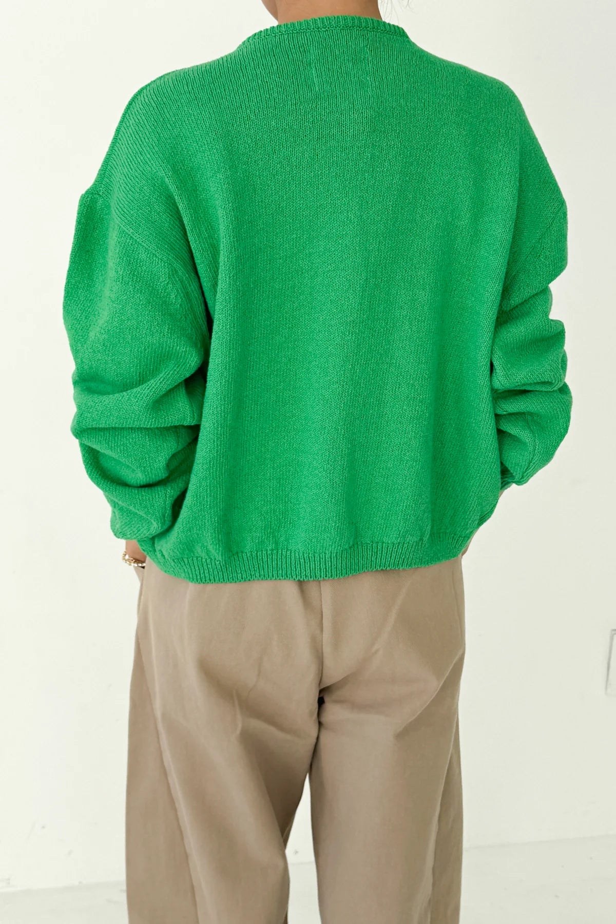 Back view of Le Bon Shoppe Cotton Leila Cardigan in spring green showing relaxed oversized silhouette, ribbed hem and cuffs, styled with cream trousers