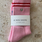 Le Bon Shoppe Embroidered Boyfriend Socks in amour pink folded and banded with Le Bon Shoppe Boyfriend Socks packaging label, showing embroidered heart and red double stripe on pink ribbed cotton