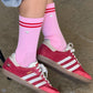 Le Bon Shoppe Embroidered Boyfriend Socks in amour pink worn with red Adidas Samba sneakers and grey sweat shorts, showing pink ribbed cotton with red double stripe and embroidered heart detail