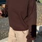 Close-up of Le Bon Shoppe French Terry Core Sweatshirt in cocoa bean showing boxy relaxed fit and raglan seam detail, styled with cream shorts against an outdoor garden background