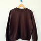 Le Bon Shoppe French Terry Core Sweatshirt in cocoa bean on a wooden hanger against a white wall, showing full boxy silhouette with ribbed crew neck, cuffs and hem