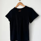 Le Bon Shoppe Go-To Tee in true black on a wooden hanger against a white wall, showing relaxed longer length silhouette, crew neck and short sleeves