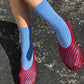 Le Bon Shoppe Her Socks in periwinkle worn with red mesh jelly ballet flats on dark asphalt, showing ribbed cotton-blend texture and quarter-crew length in natural sunlight