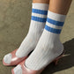 Le Bon Shoppe Her Varsity Socks in periwinkle worn front-on with pink open-toe leather heels showing white ribbed sock with periwinkle double stripe and quarter-crew length