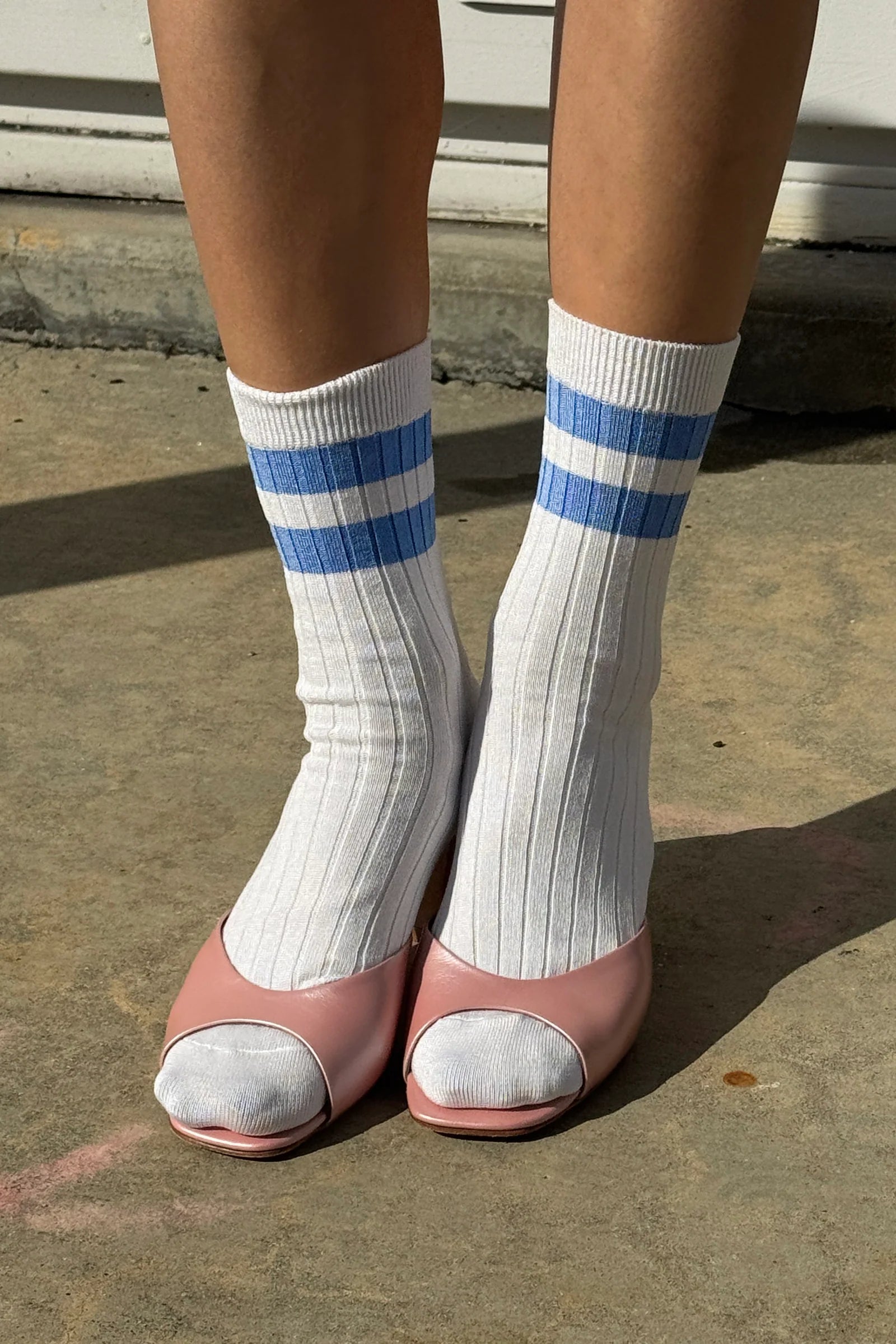Le Bon Shoppe Her Varsity Socks in periwinkle straight-on view with pink open-toe heels, showing full quarter-crew length and periwinkle double stripe on white ribbed cotton-blend