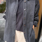Close-up of Le Bon Shoppe Theo Jacket in black denim showing button front placket and contrast stitching, layered over a black tee with cream trousers