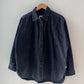 Le Bon Shoppe Theo Jacket in black denim on a wooden hanger against a grey wall, showing full oversized silhouette, button front and rounded hem