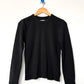 Le Bon Shoppe Waffle Fundamental Tee in true black on a wooden hanger against a white wall, showing full long-sleeve silhouette, crew neck and baby ribbed cuffs in heavyweight waffle cotton