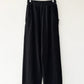 Le Bon Shoppe Waffle Lo Pants in true black on a hanger against a white wall, showing full wide leg silhouette, elastic waistband, front pockets and signature arc seam in heavy waffle cotton