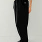 Side profile of Le Bon Shoppe Waffle Lo Pants in true black showing signature arc seam detail, elastic waistband and relaxed silhouette, styled with cream Waffle Fundamental Tee